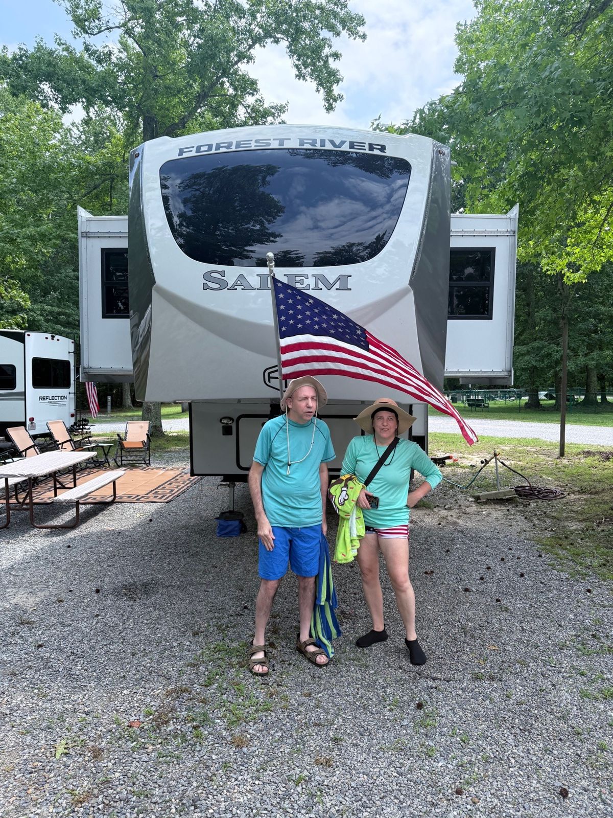 The front of our fifth wheel with J and J standing by the flag
